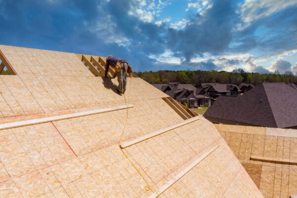 Ouvrier construisant un toit sur maison neuve.